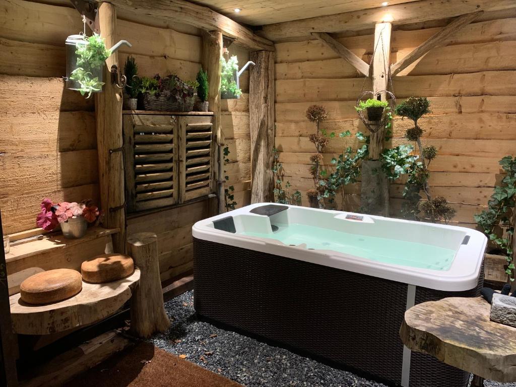 Habitación de madera con baño con bañera. en Boutique Cottage - Sauna and Jacuzzi - El Clandestino, en Érezée