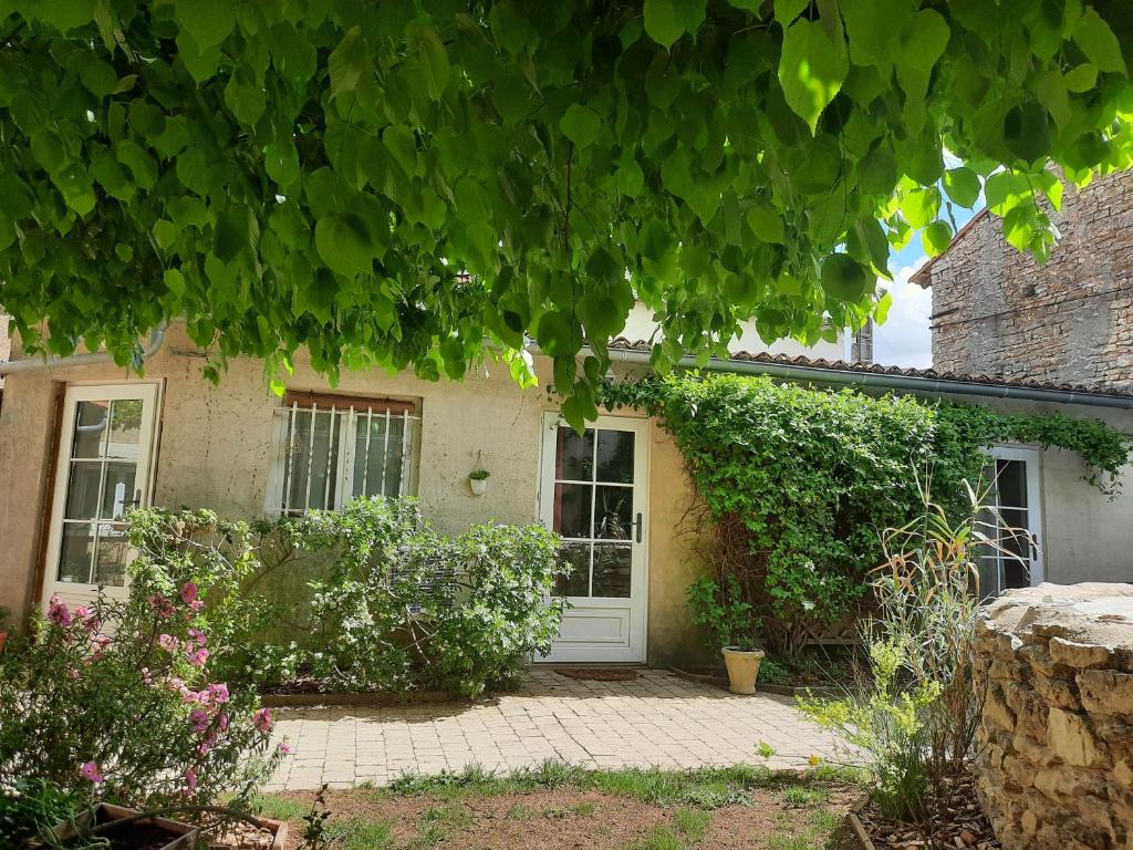 Vendeuvre-du-Poitou的住宿－Le clos du coteau，一座有白色门和一些植物的房子