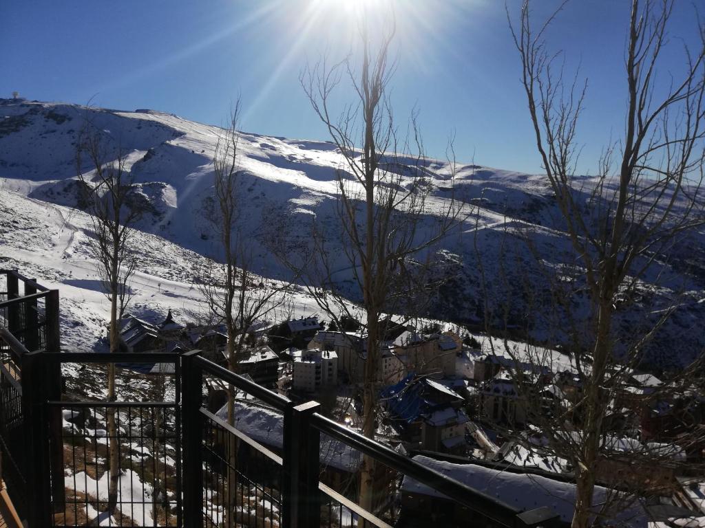 con vistas a una montaña cubierta de nieve y al sol en APARTAMENTO LOS VALLES en SIERRA NEVADA Parking gratuito, en Sierra Nevada