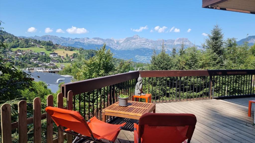 una terraza de madera con sillas y una mesa con vistas a las montañas en Chalet du Vernay, en Saint-Gervais-les-Bains