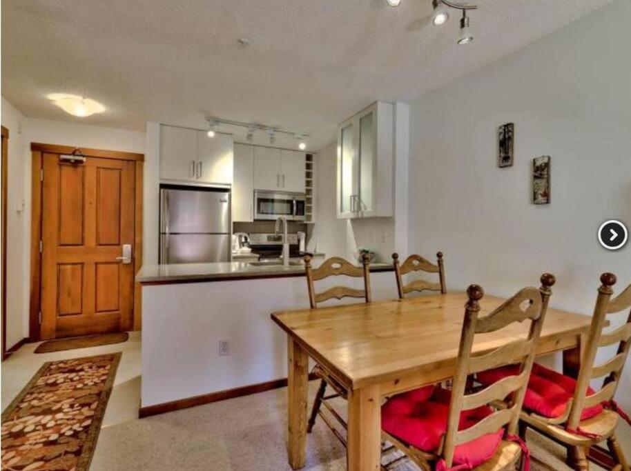a kitchen and dining room with a wooden table and chairs at Beautiful true ski-in/out condo for family trip! in Sun Peaks