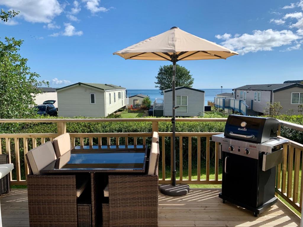 a grill and an umbrella on a deck at Lydstep Beach BayView 3-Bedroom Holiday Home in Tenby