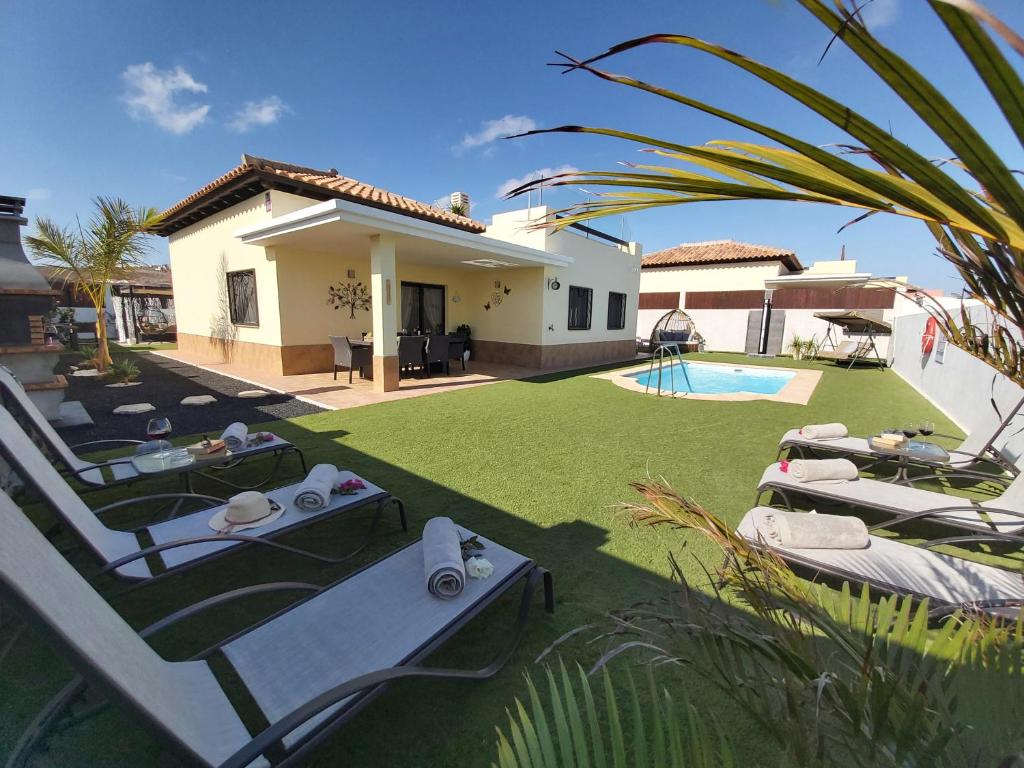 a house with a yard with chairs and a swimming pool at Villa Thais, private heated pool, ideal for your holidays in Caleta de Fuste in Caleta De Fuste