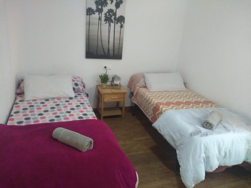 Habitación con 2 camas y mesa con mesita de noche. en CasaAlicante Private Apartment Condo for up to 5 people Zentrale Wohnung AC Bedroom Klimaanlage, en Alicante