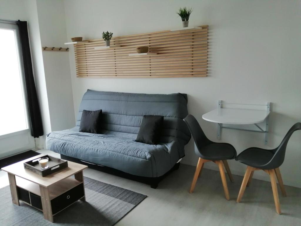 ein Wohnzimmer mit einem Sofa und einem Tisch in der Unterkunft STUDIO NOYANT VILLAGES in Noyant
