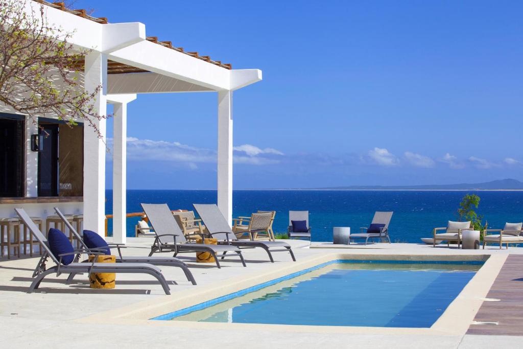 La VentanaHotel Todo Bien的一组椅子和一个毗邻大海的游泳池