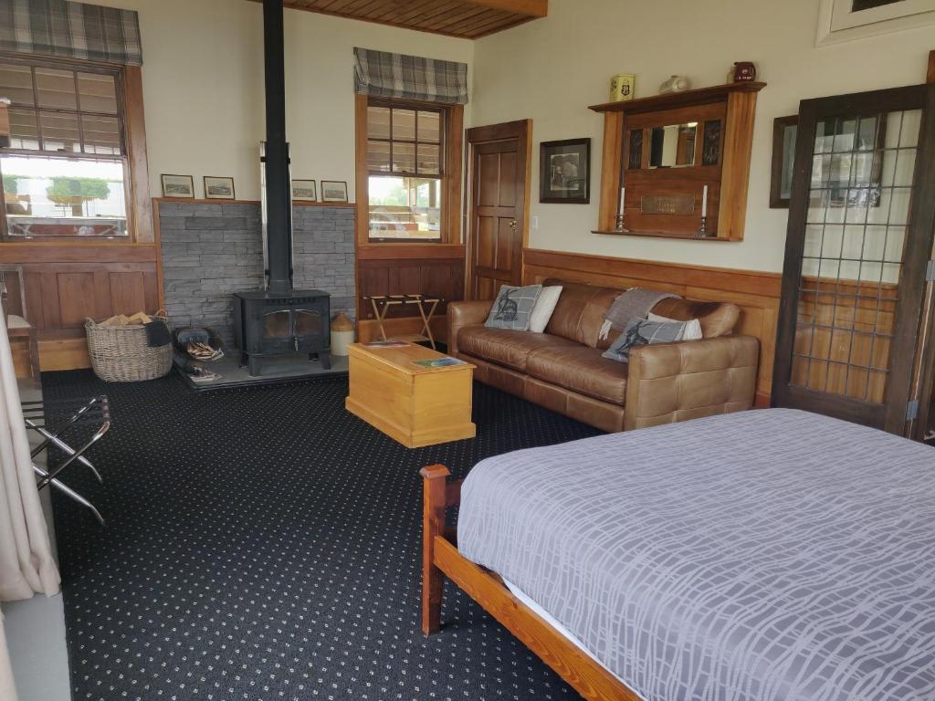 ein Schlafzimmer mit einem Bett, einem Sofa und einem Kamin in der Unterkunft Bramley's Stables and Accommodation in Rangiora