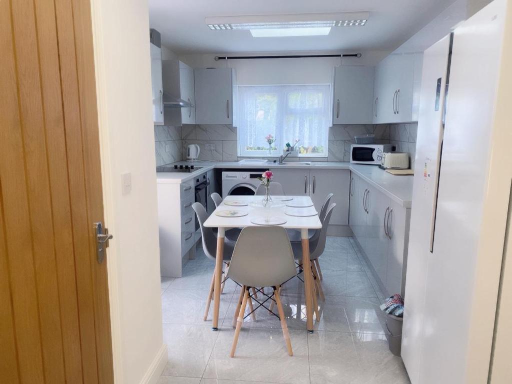 a white kitchen with a table and chairs in it at The Grove 7 Bedroom, 7 Showers, 8 Beds, 8 toilets Beautiful House in Plumstead