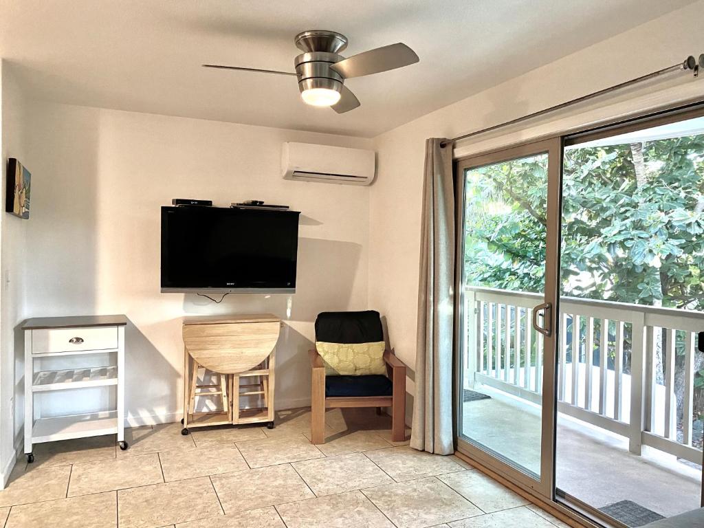 ein Wohnzimmer mit einem TV und einem Balkon in der Unterkunft Beach Side Studio by Shark's Cove in Haleiwa