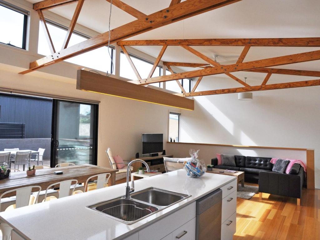 a kitchen and living room with exposed beams at Luxe Townhouse 2 in Inverloch