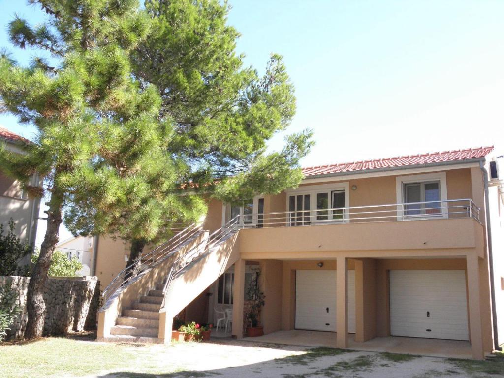 une maison avec des escaliers et un arbre en face de celle-ci dans l'établissement Apartments Remi - 300m from sea, à Nin