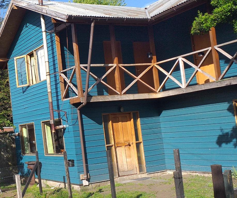 a blue house with a porch and a wooden door at Hospedaje Picoyo in Pucón