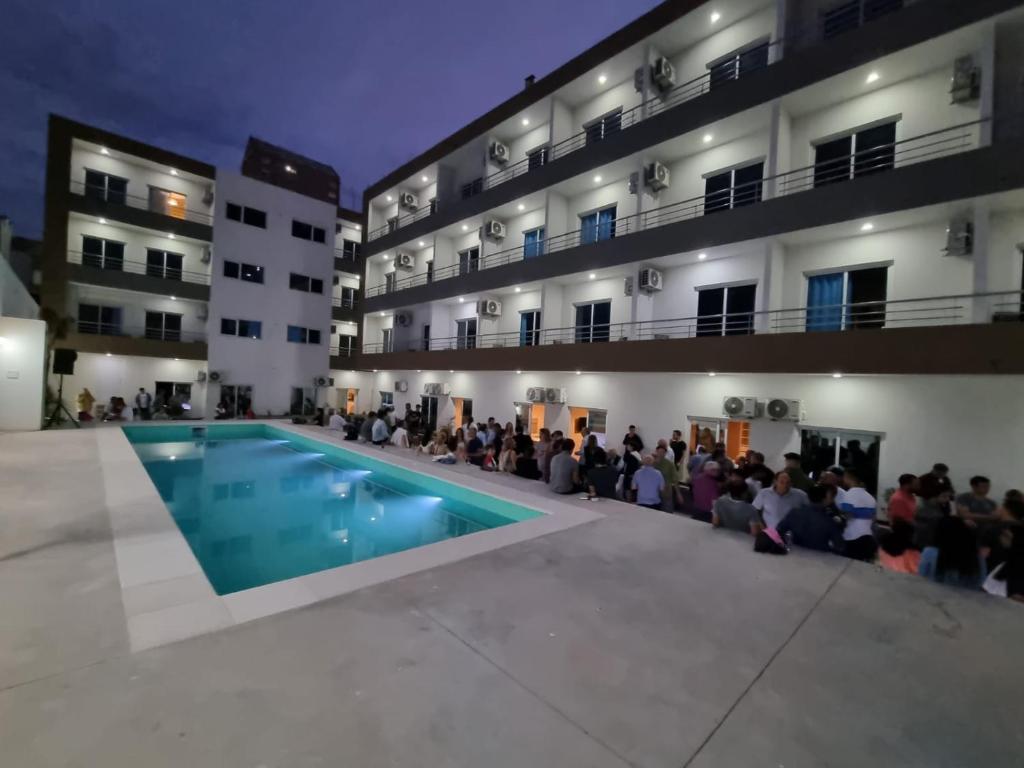 a crowd of people sitting around a pool in front of a building at Casa de Playa in Necochea