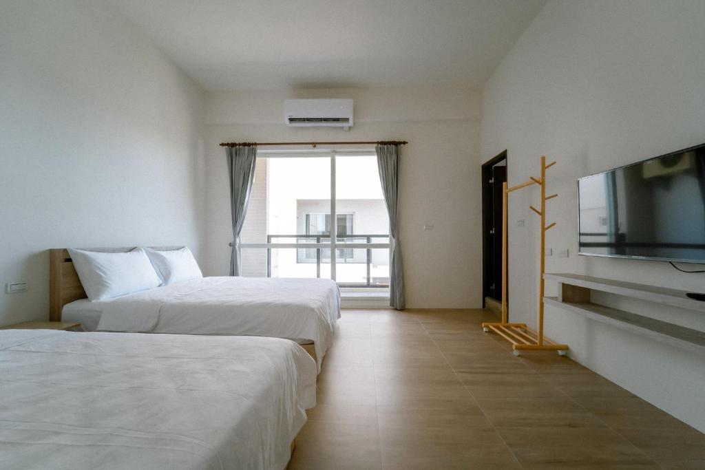 ein Hotelzimmer mit 2 Betten und einem Flachbild-TV in der Unterkunft 澎湖逸軒居民宿 in Huxi