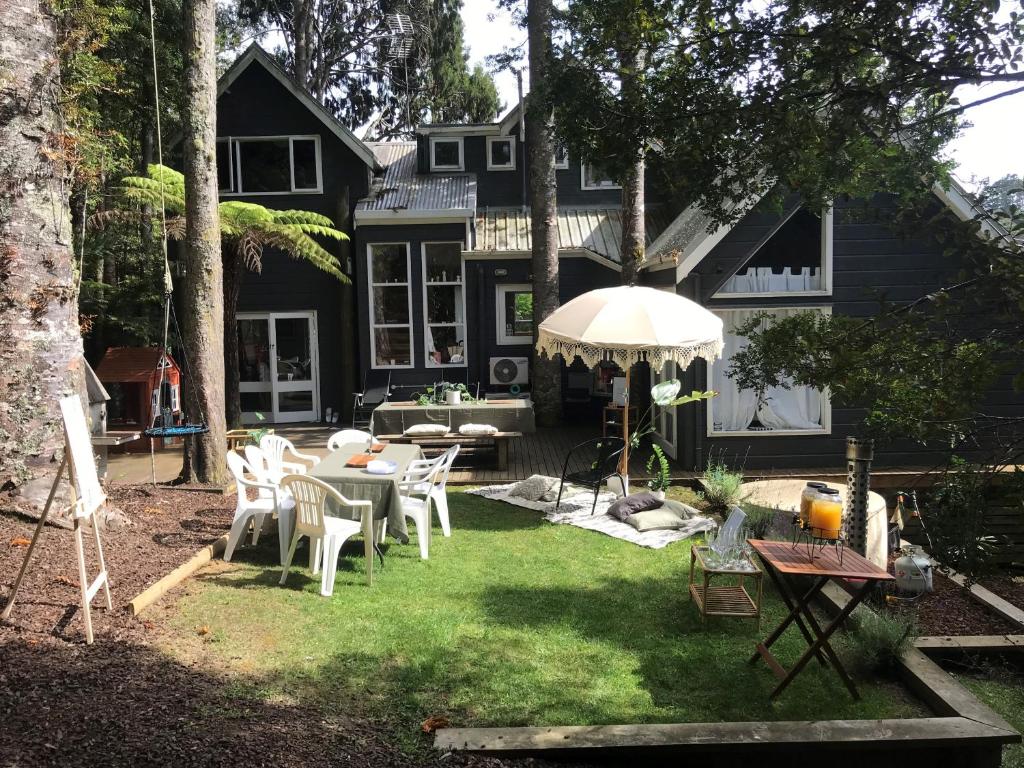 a backyard with a table and chairs in front of a house at Titirangi Paradiso in Titirangi