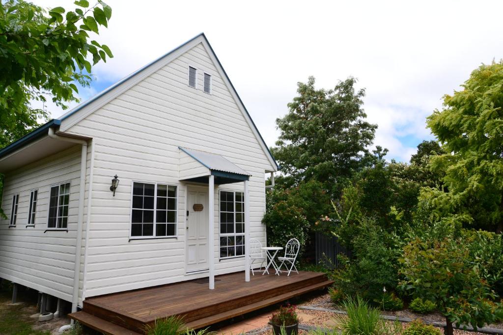 a white house with a porch and a deck at Briar Rose Cottages in Stanthorpe