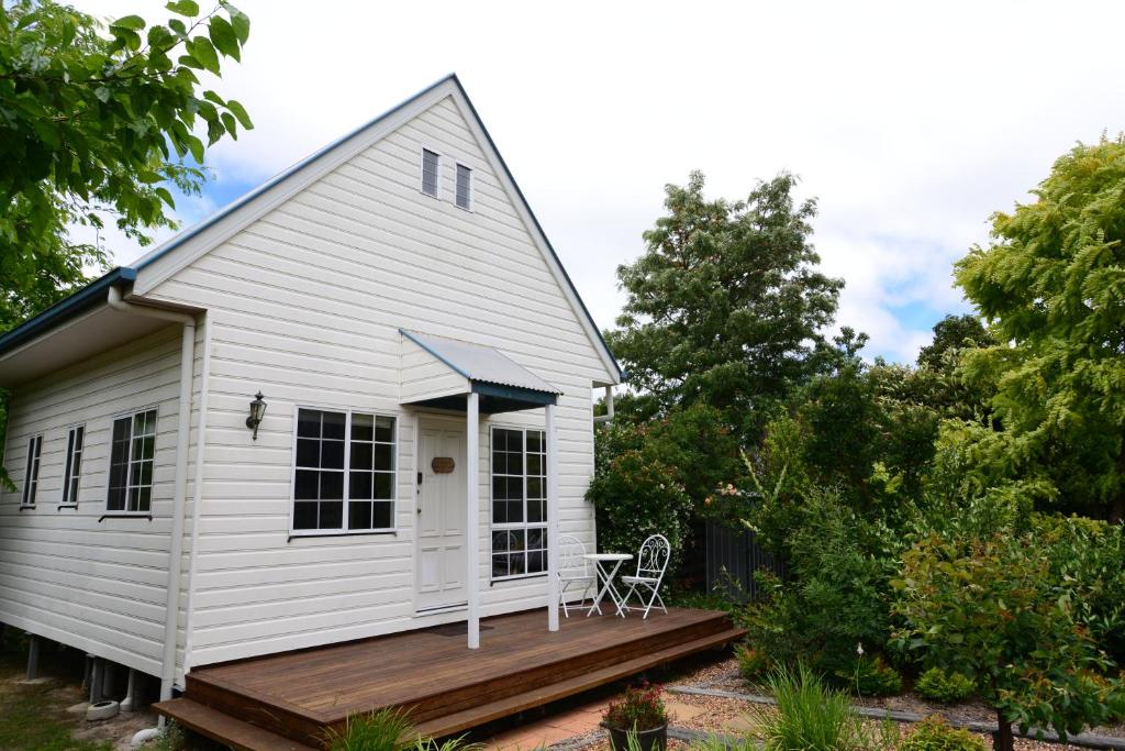 una casa bianca con portico e terrazza di Briar Rose Cottages a Stanthorpe