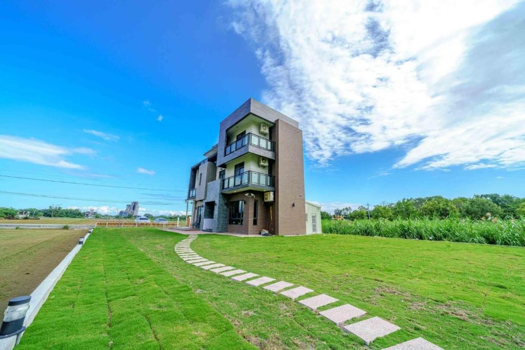 a building with a grassy field in front of it at 豐生活海館包棟民宿-按照人數開放客房數量 Manbo Beach Fengst-ay Ocean Villa-Number of rooms according to occupancy in Shunan