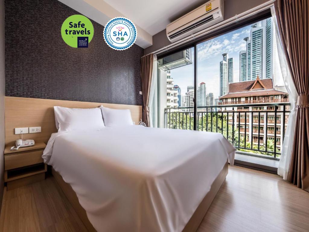 a bedroom with a large white bed and a large window at Like Sukhumvit 22 in Bangkok