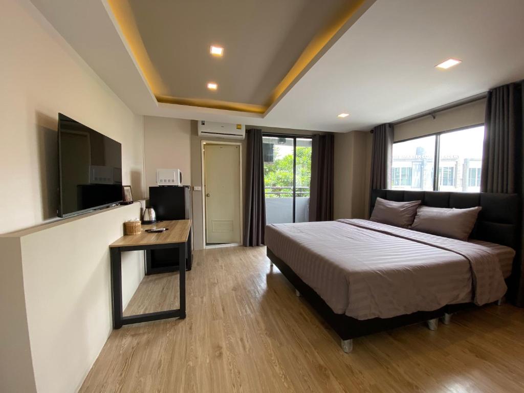 a bedroom with a bed and a desk and a television at Bansuay Bangkadi in Pathum Thani