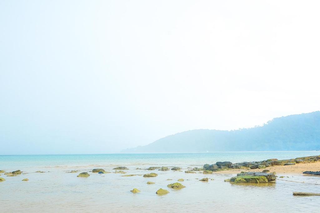 a beach with some rocks in the water at Lazy Bones in Koh Rong Sanloem