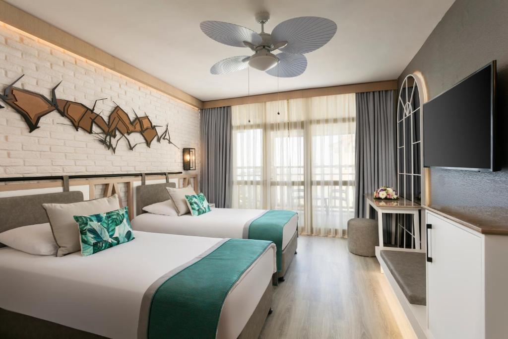 a hotel room with two beds and a flat screen tv at Limak Arcadia Sport Resort Belek in Belek
