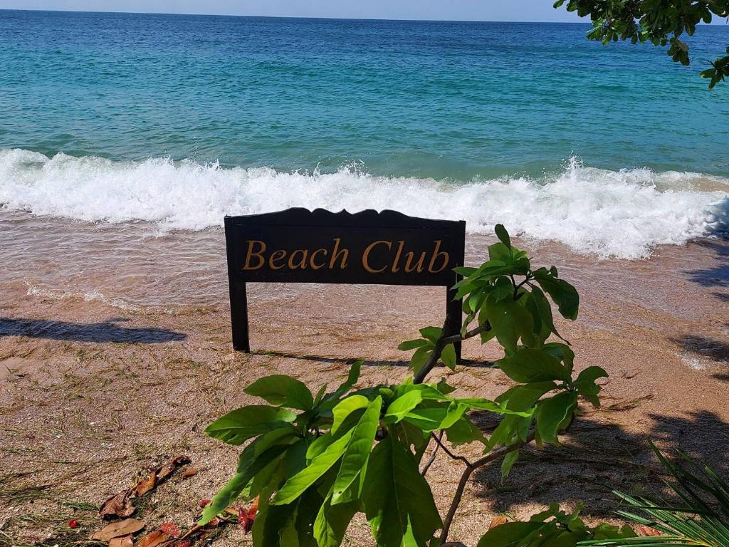 una señal de club de playa en la playa cerca del océano en Koh Tao Beach Club en Ko Tao