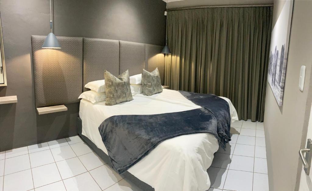 a bedroom with a large bed with white sheets and pillows at Adventure Apartment - Addo Elephant Park South Entrance only 5km in Colchester