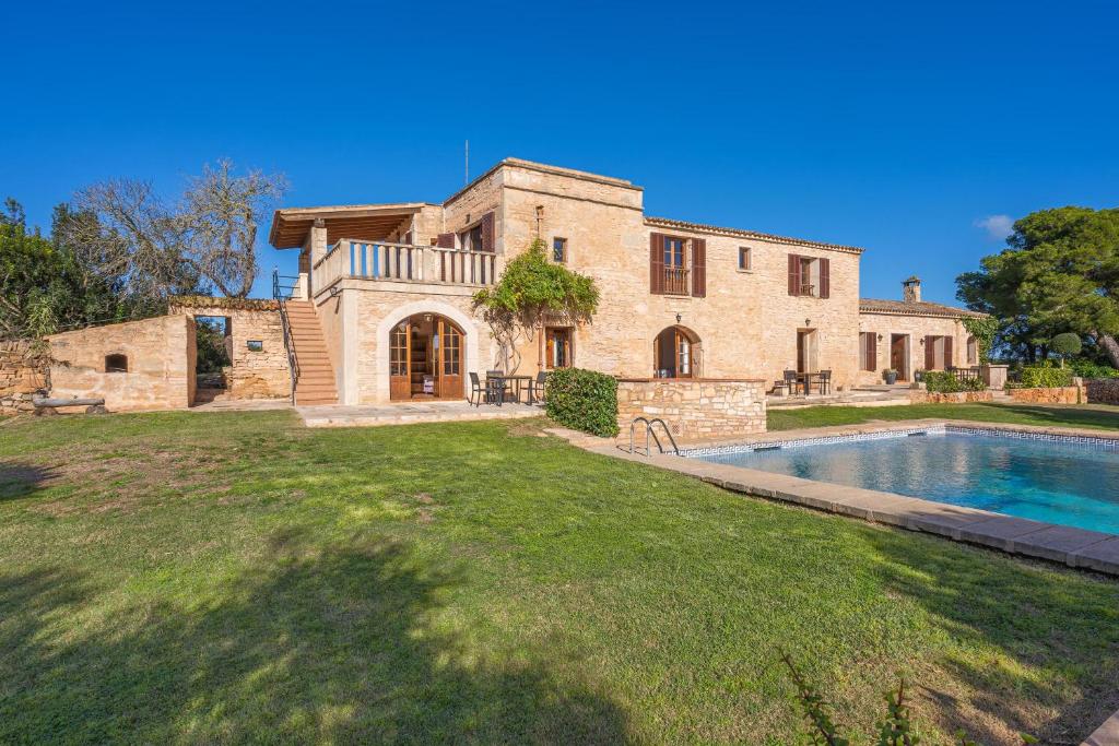 una gran casa de piedra con piscina frente a ella en Es turo de Formentera en Ses Salines