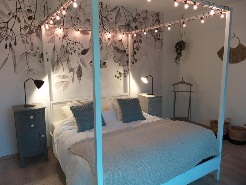 ein Schlafzimmer mit einem Himmelbett mit Beleuchtung in der Unterkunft La Maison de Sidonie in Jalhay