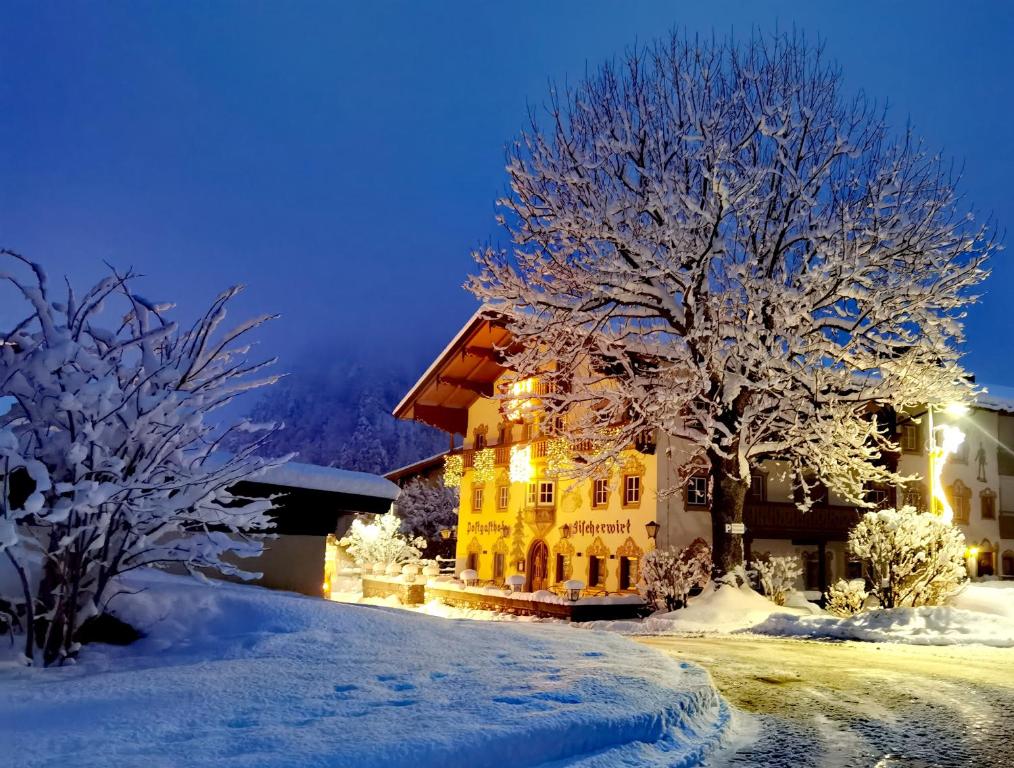 una casa nella neve di notte di Postgasthof Fischerwirt a Walchsee
