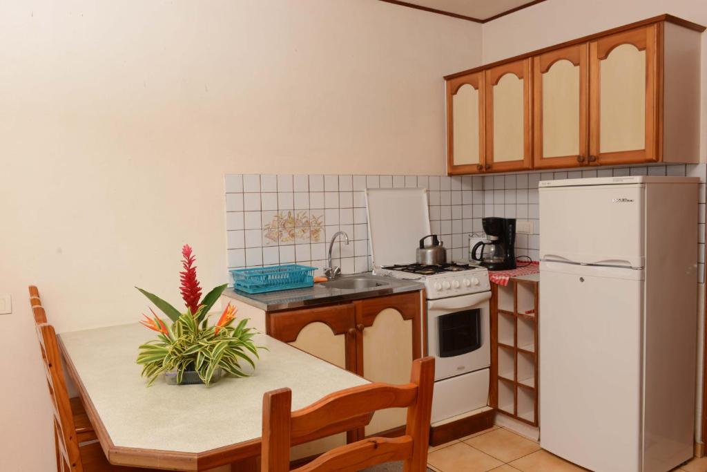 a kitchen with a table and a white refrigerator at Pension de famille HITI MOANA VILLA in Papara