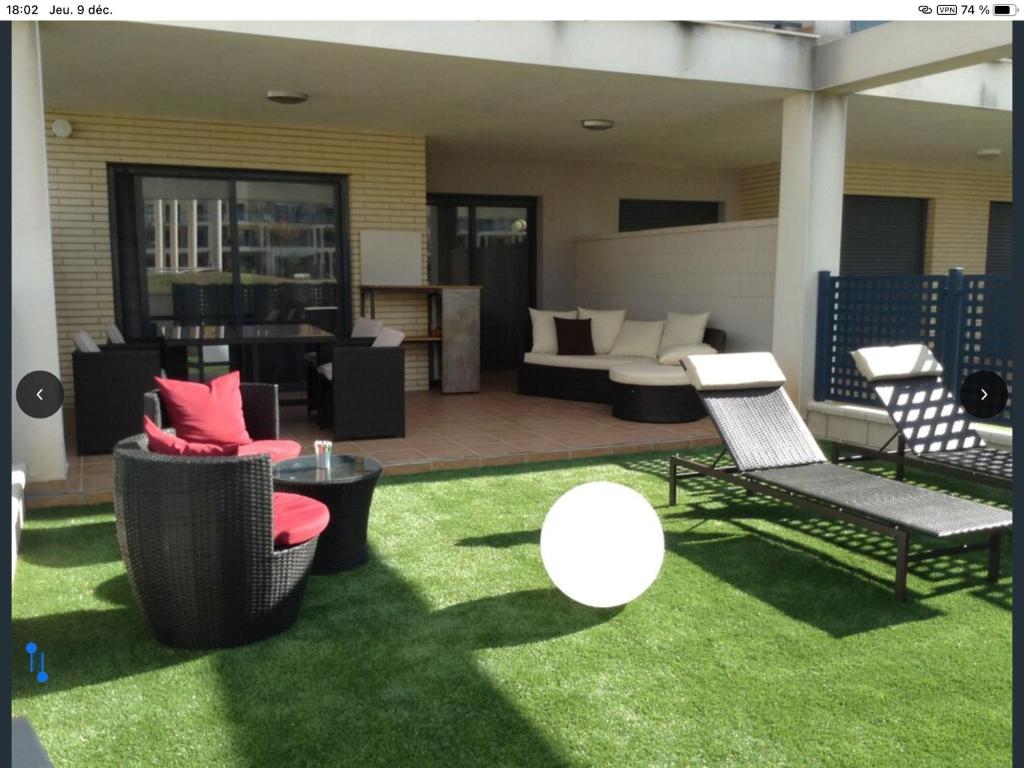 a patio with chairs and tables on grass at Appartement Golf PANORAMICA in Sant Jordi