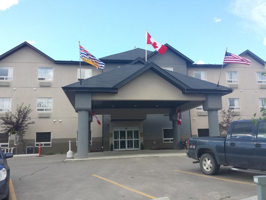 
a large building with a flag on top of it at Sigma Inn & Suites Hudson's Hope in Hudson Hope
