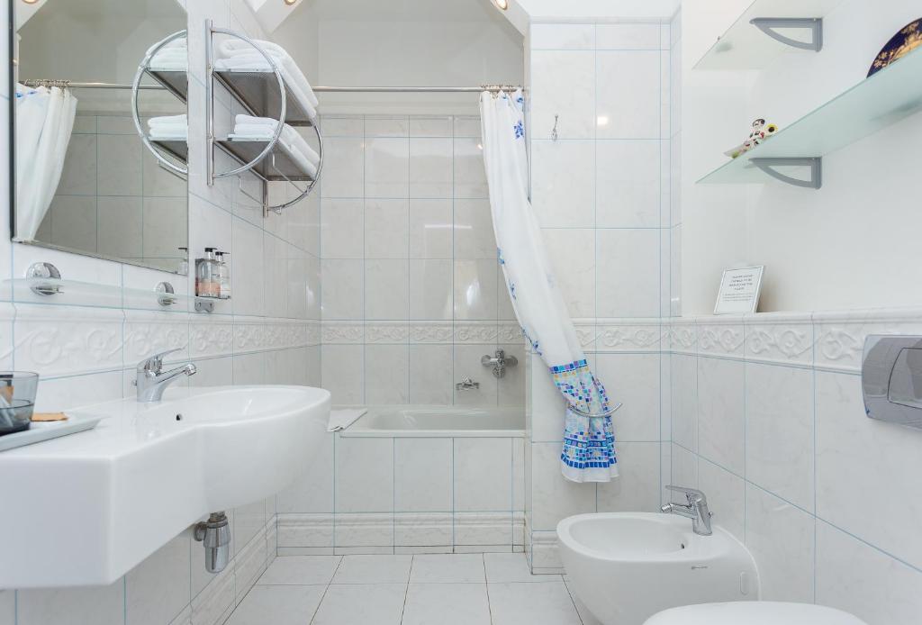 a white bathroom with a sink and a tub and a toilet at Casa Leto in Saint Petersburg