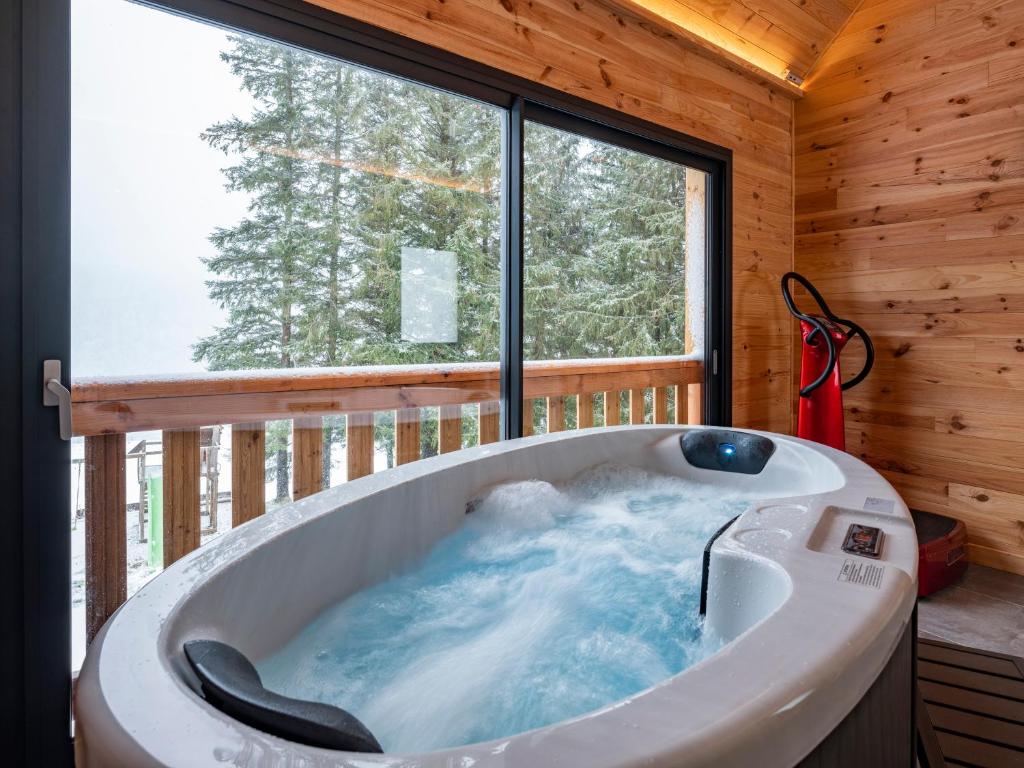 a tub in a cabin with a large window at Chalet Pom'Pin in Le Mont-Dore