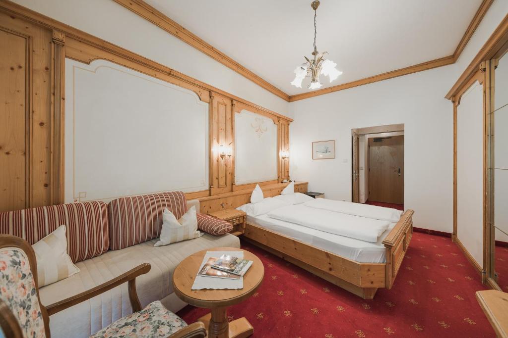 een hotelkamer met een bed en een bank bij Hotel Sonklarhof in Ridanna