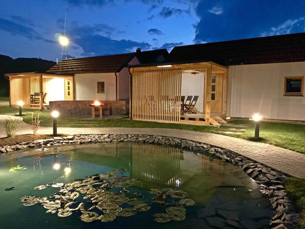 une maison avec un étang dans la cour la nuit dans l'établissement Ribiška vasica - Fishermen's Village, à Radeče