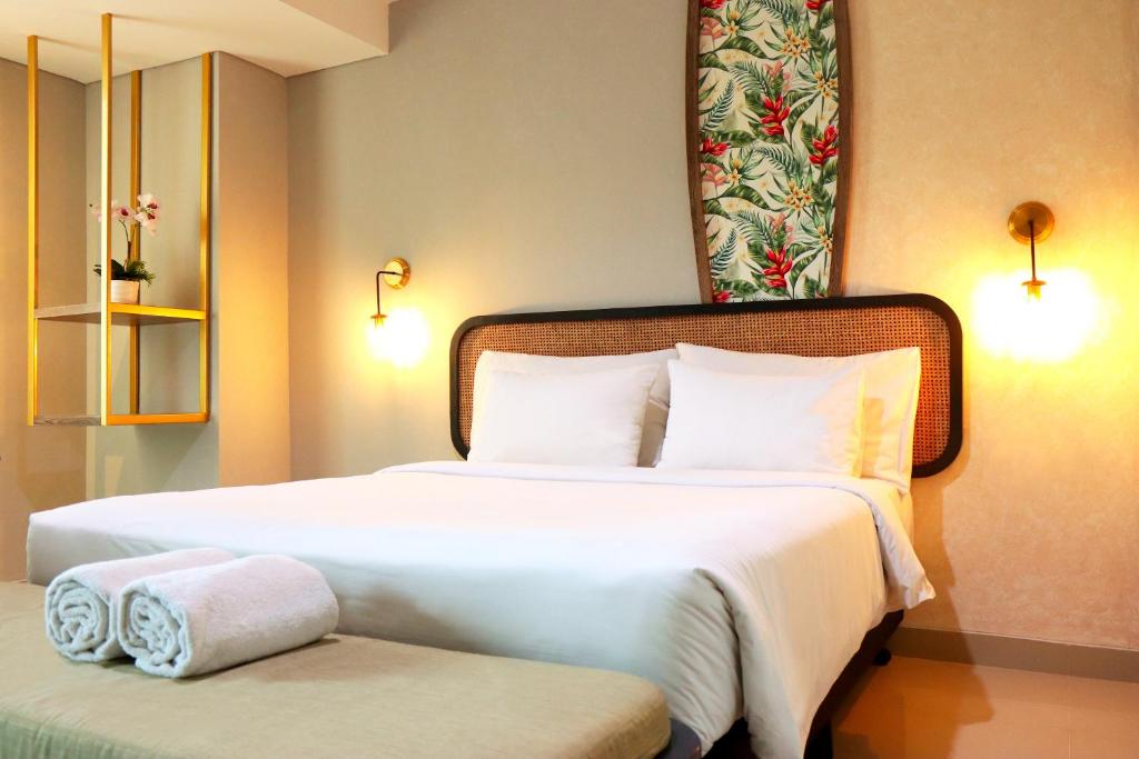 a hotel room with two beds and a bench at StayG Eastern Green by GranDhika - Bekasi in Padurenan