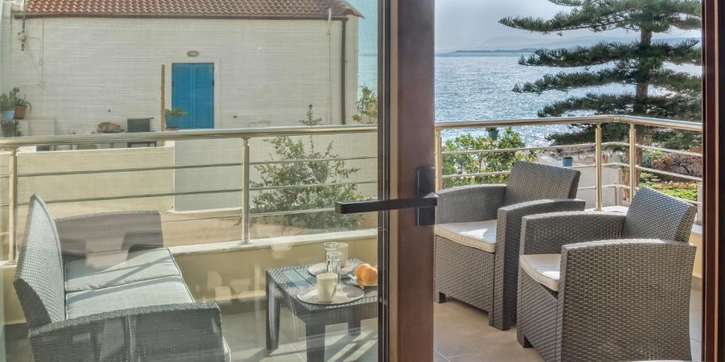 balkon z krzesłami i stołem z widokiem na ocean w obiekcie Seaview Apartment SUNRISE Near To Falassarna Beach w mieście Kolimvari