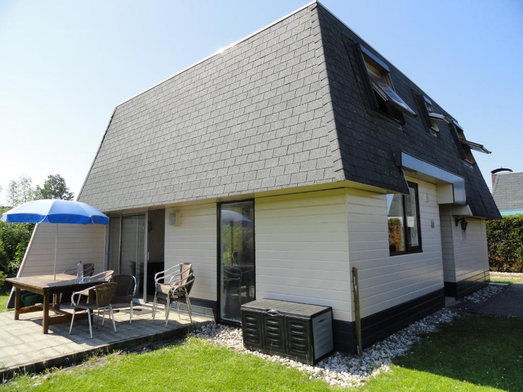een huis met een patio en een tafel met een parasol bij Kustverhuur, Park Schoneveld, Zeester 27 in Breskens