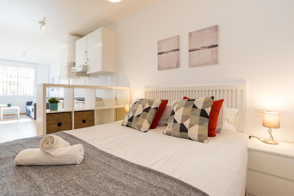 a white bedroom with a large bed with pillows at Modern studio apartments Benalmadena in Benalmádena