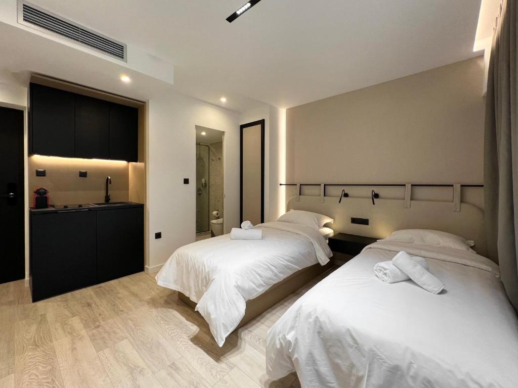 a bedroom with two beds with white sheets at ICON Urban Living in Thessaloniki