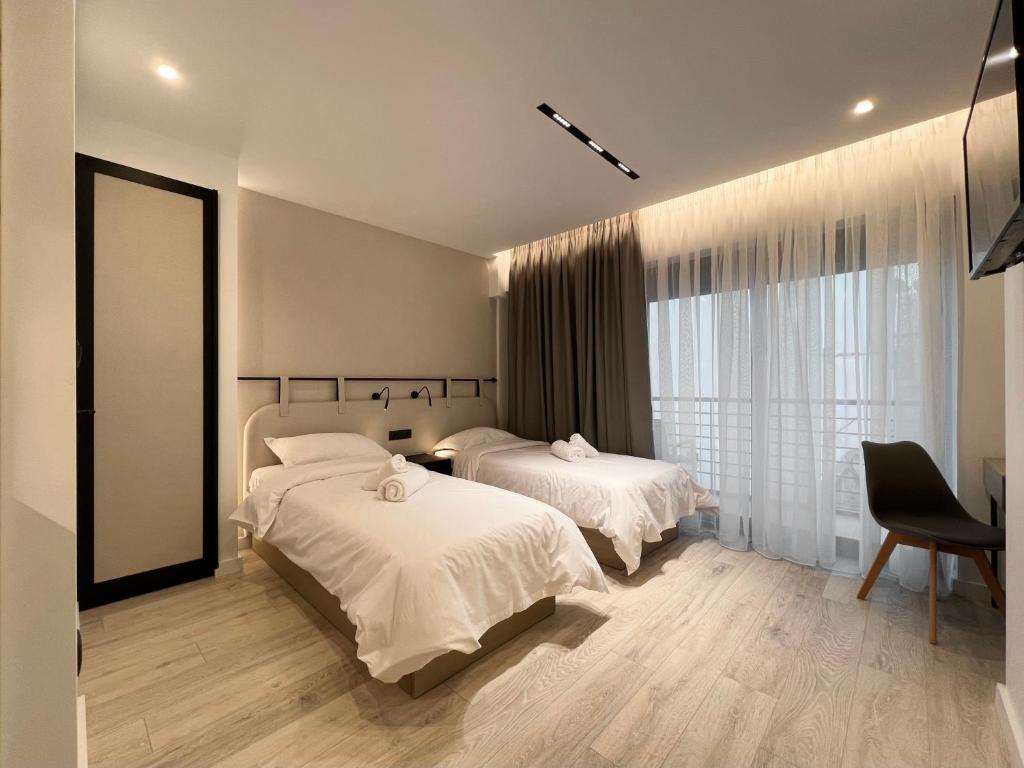 a bedroom with two beds and a large window at ICON Urban Living in Thessaloniki
