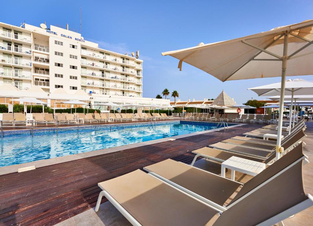 a swimming pool with lounge chairs and a hotel at Globales Cala'n Bosch in Cala en Bosc