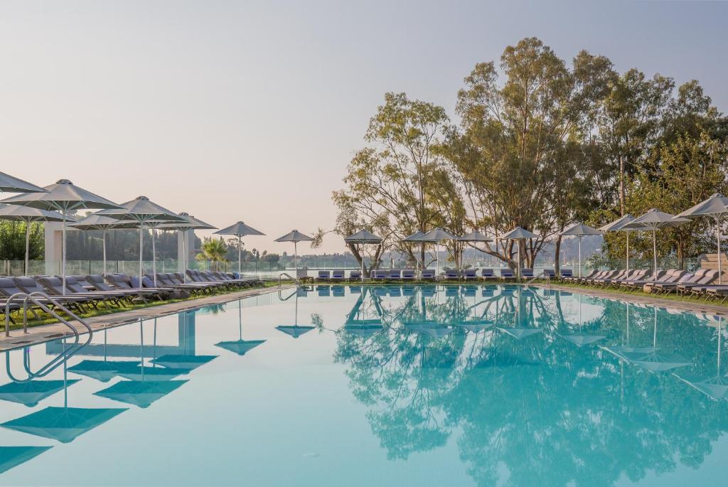 a swimming pool with chairs and blue water at Rodostamo Hotel & Spa- Adults Friendly in Kommeno
