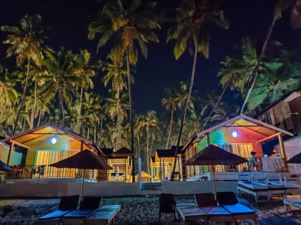 a resort with chairs and palm trees at night at Next ta Sea in Palolem