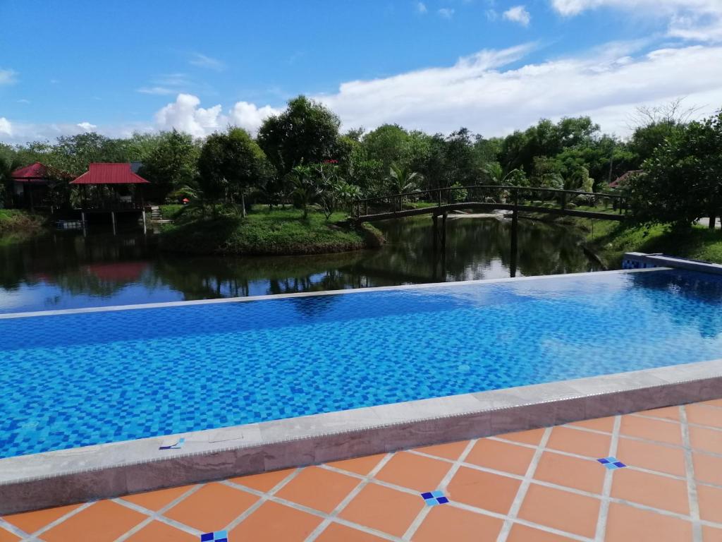 a swimming pool at a resort with a bridge over a river at Api-api Eco Chalet in Pantai Kok