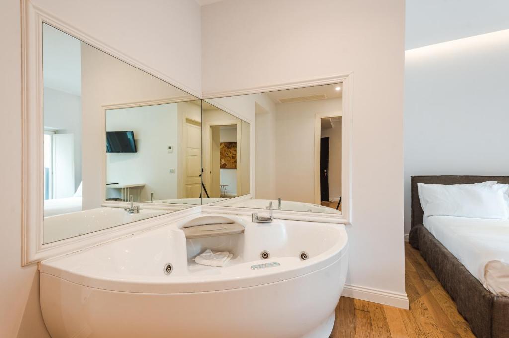 a bathroom with a tub and a bed and a mirror at Nikis Collection Trastevere in Rome