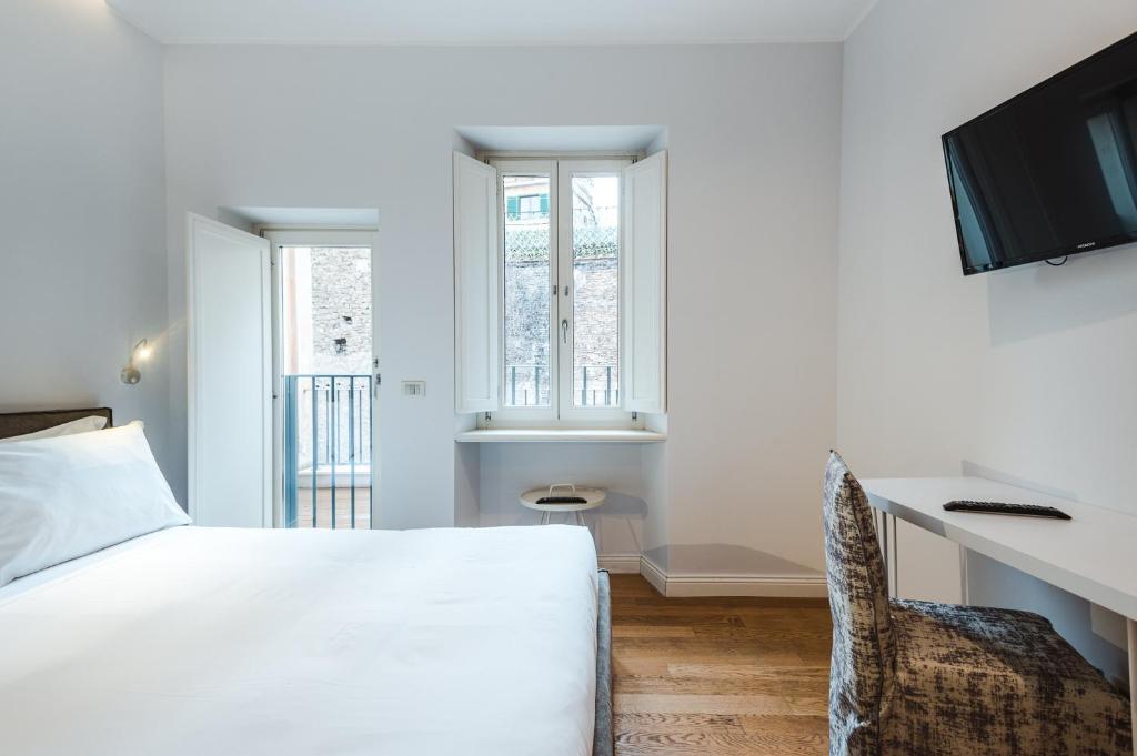 a bedroom with a white bed and a desk and a chair at Nikis Collection Trastevere in Rome